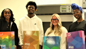 Four UNCG CARS students hold up boxes containing Archroma Color Atlas donation
