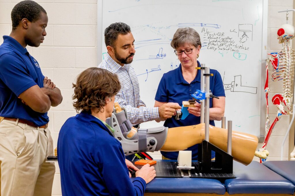 Professors and students gather around model of a knee in Kinesiology class