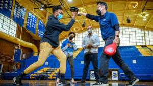 Yongsun Lee practices Taekwondo with a high school student inside the basketball court