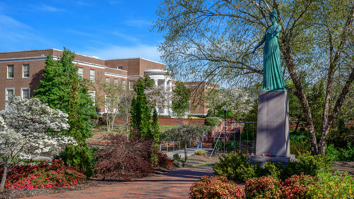 Minerva statue surrounded by spring flowers and trees on UNCG campus