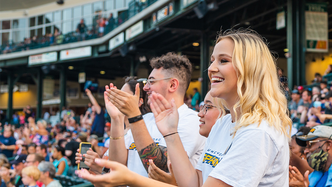 UNCG family claps in stands of Greensboro Grasshoppers stadium