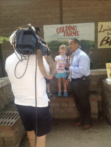 UNCG alum Chris Lea interviews little girl at farm in front of news camera