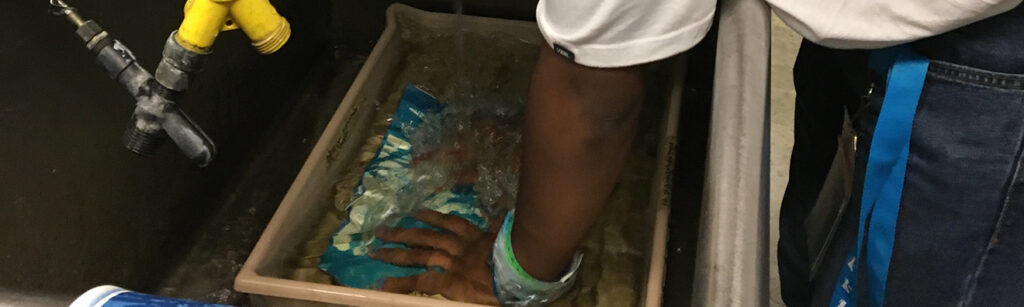 A student in a wetroom processes film.