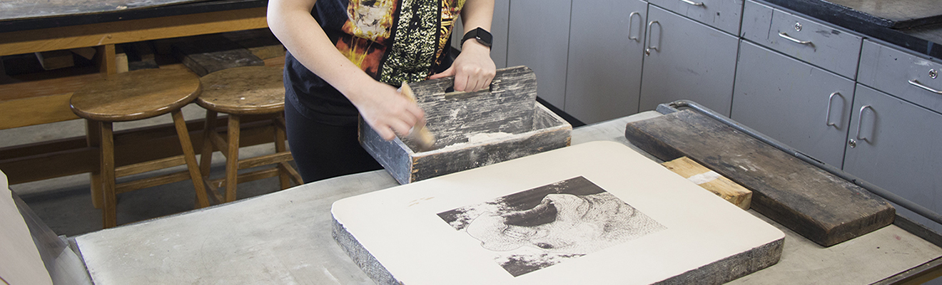 A printmaking student transfers an image from limestone.