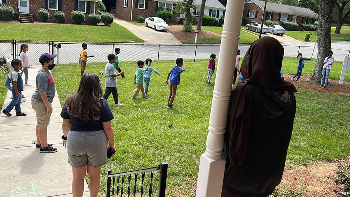 UNCG Student Volunteer watching children playing at the Center for New North Carolinians
