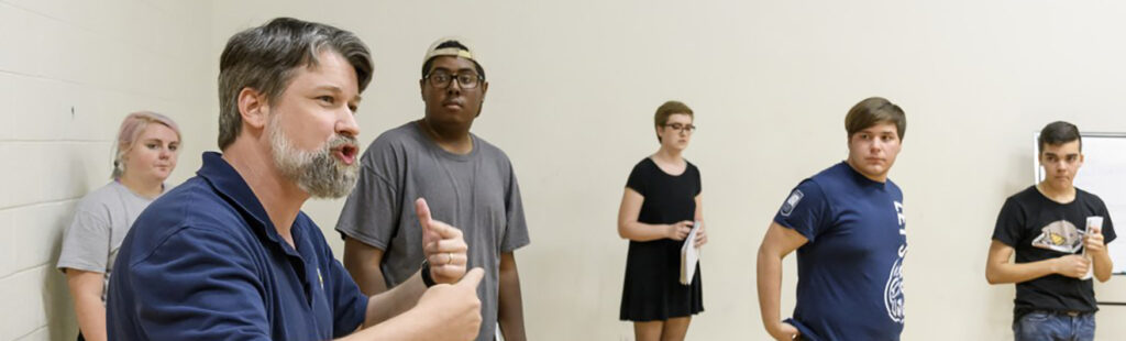 A faculty member instructs students in an acting studio.