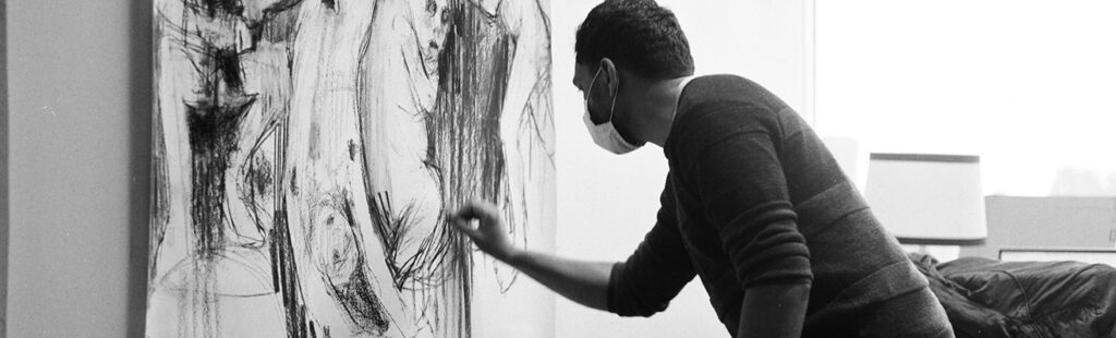 An MFA Student completing a charcoal drawing.