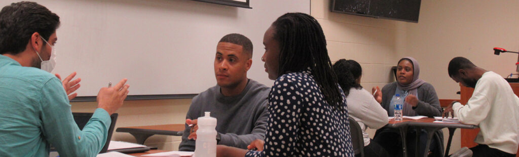 Students taking a course together, are sitting in a room discussing ideas.