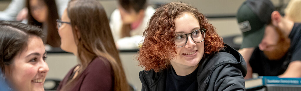 A group of students in a classroom working and discussing in small groups.