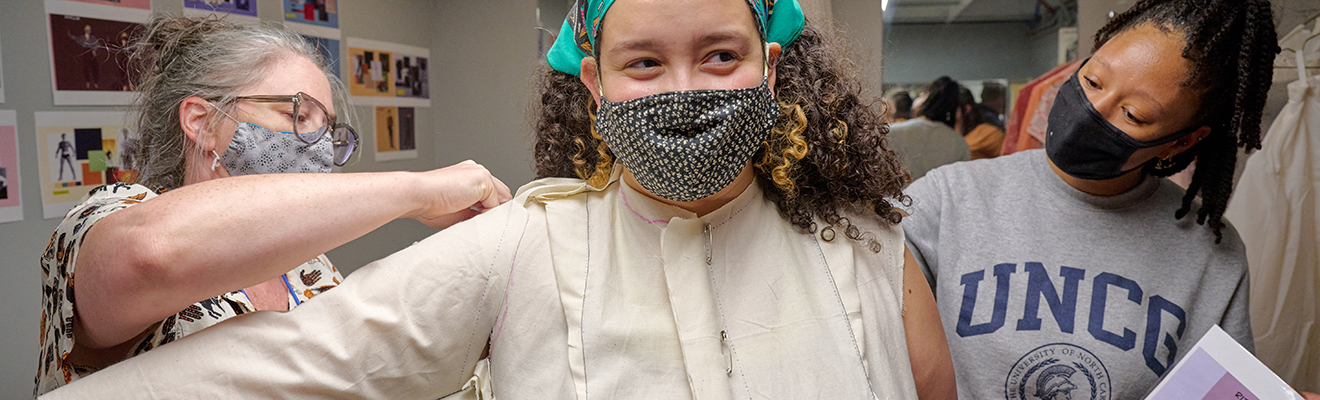 A faculty member assists a student as she creates a wig