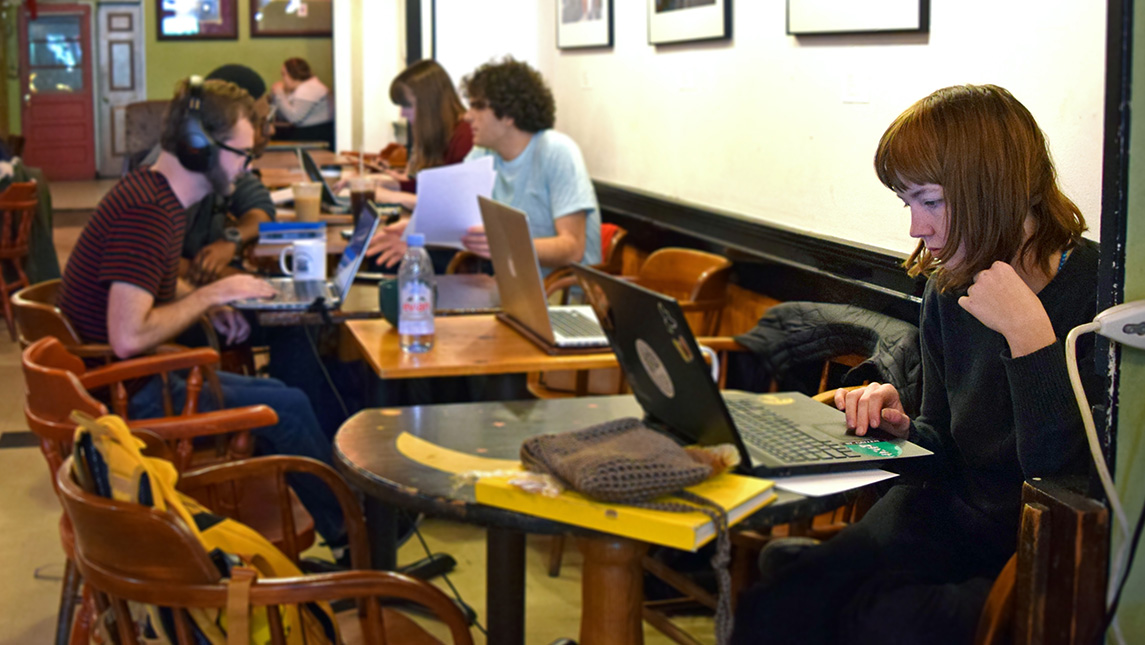 Students do school work on their laptops in a cafe.