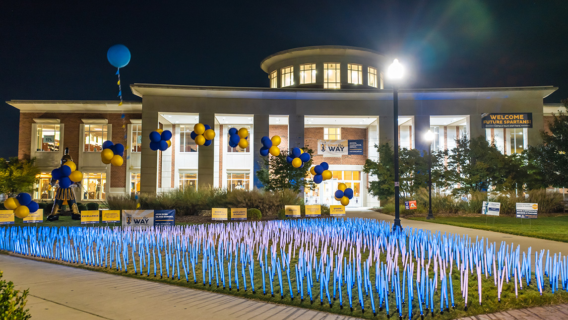 Blue and yellow light sticks are installed on the EUC lawn in celebration of UNCG Founders Day.