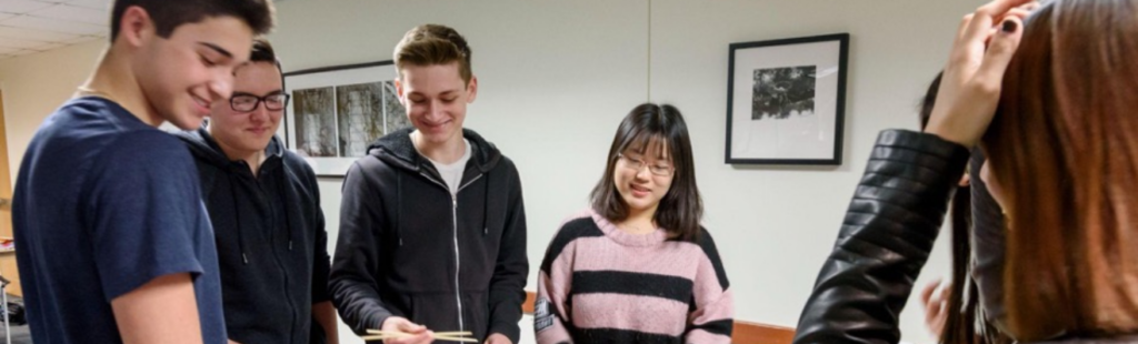 A group of young students gathered around a map, working together on a project.