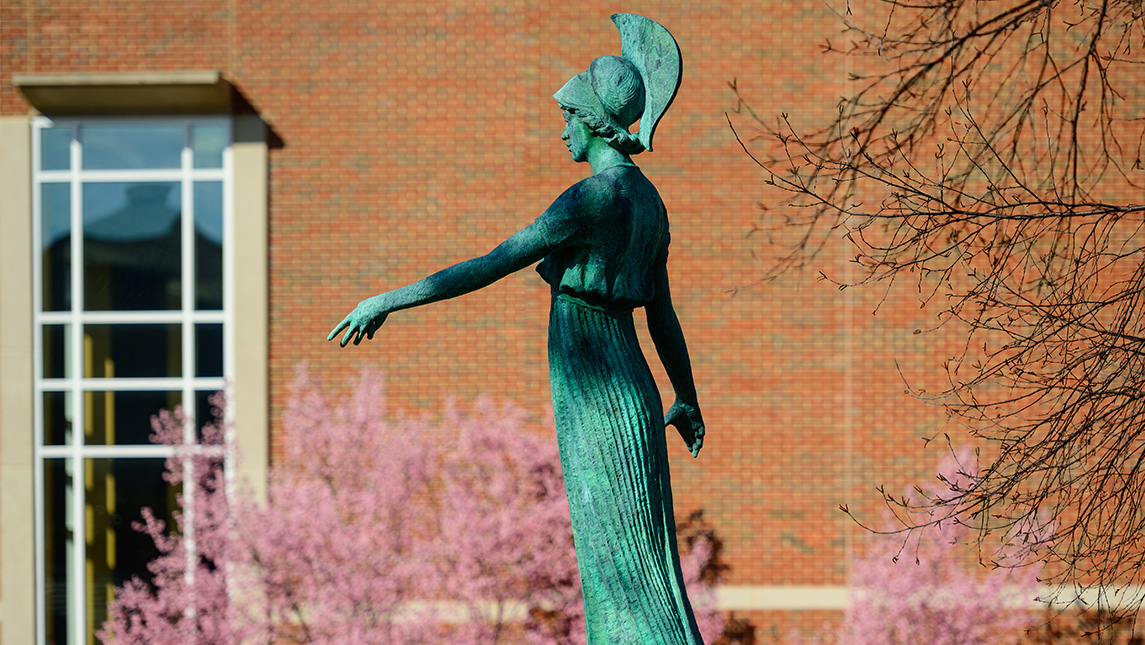 Spring blossoms fill trees around the Minerva statue on UNCG campus.
