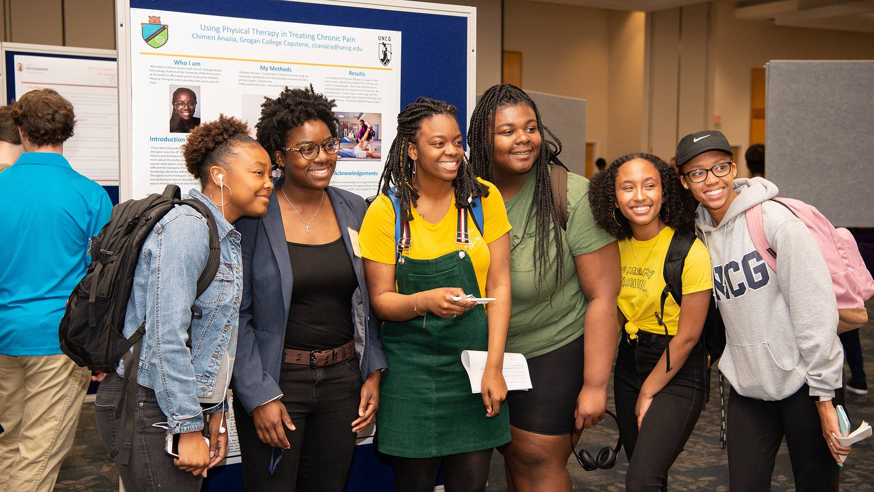 A group of female UNCG students pose for a photo at a capstone presentation.
