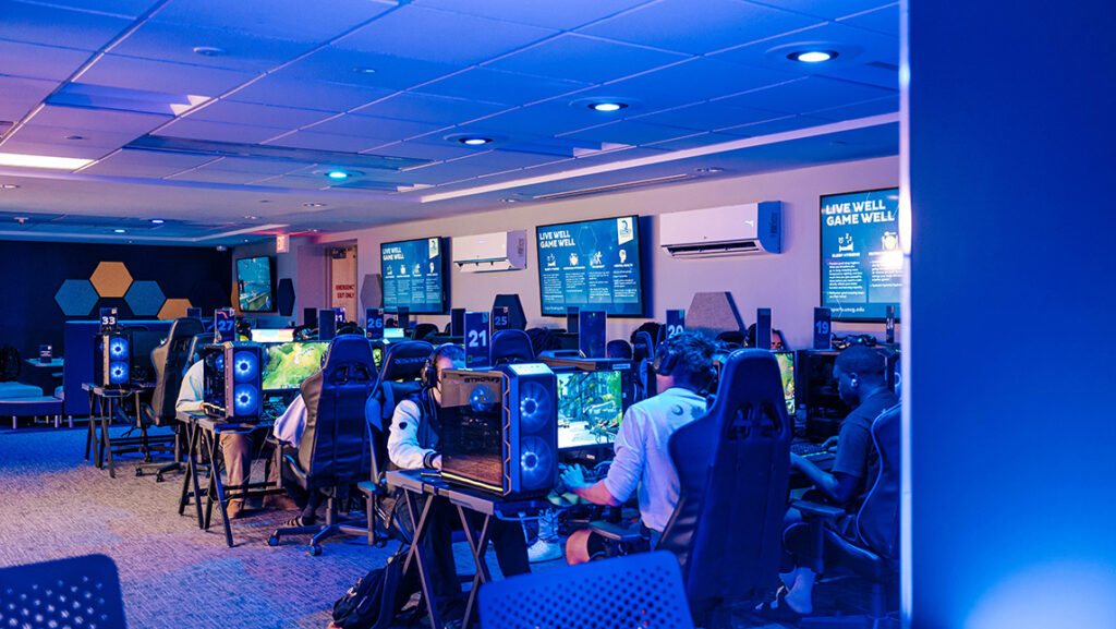 A blue-lit esports arena with people playing video games