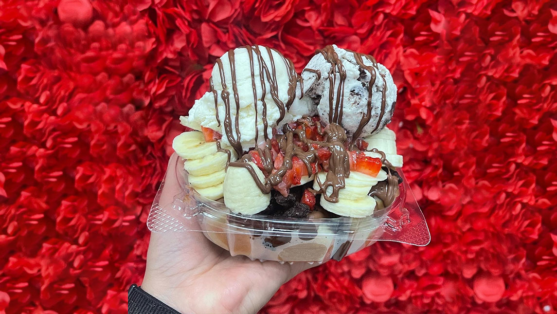 Dessert of ice cream, bananas, strawberries, with chocolate syrup drizzled on top