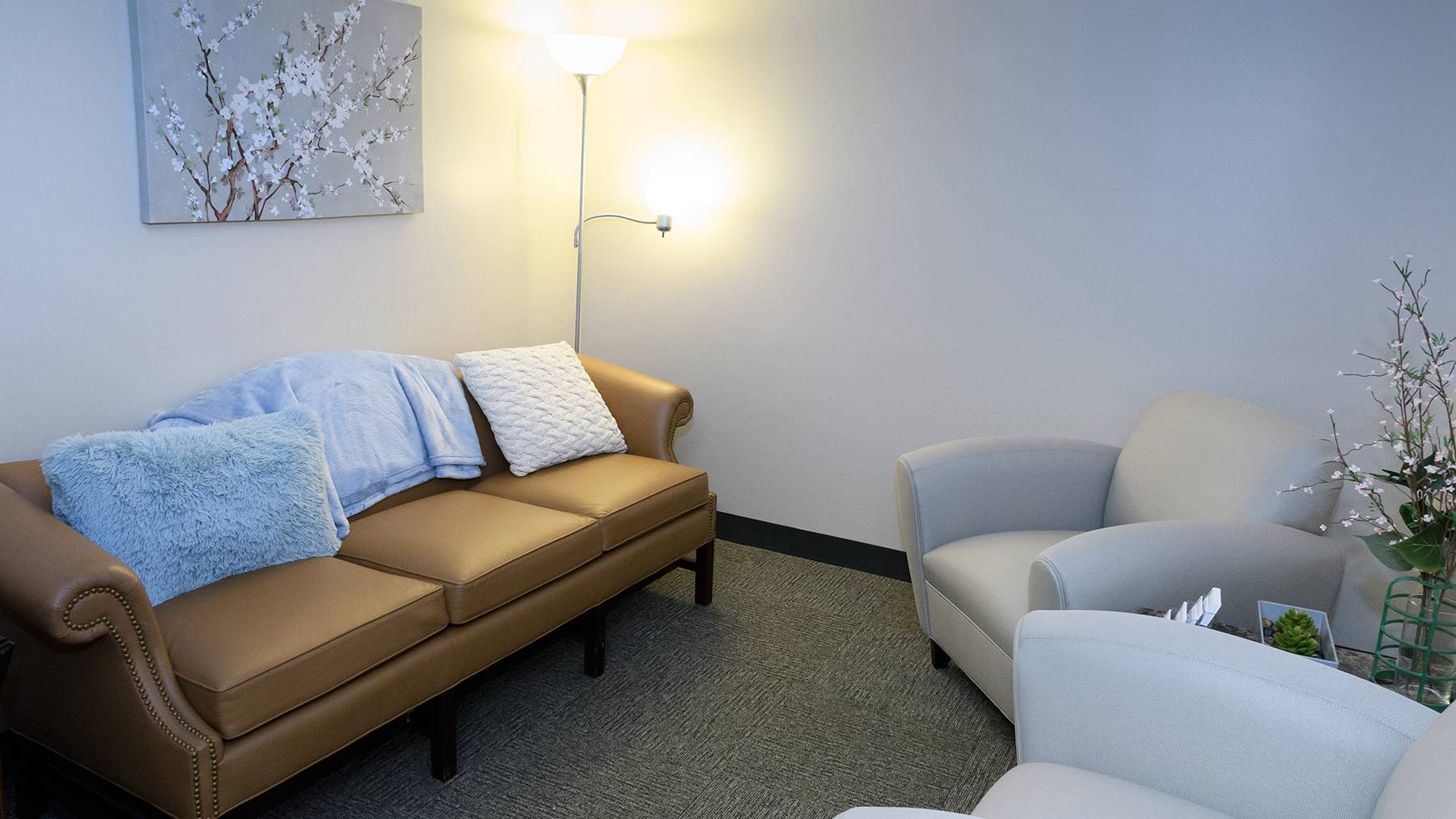 An area of the Campus Violence Response Center is shown with soft lighting, a couch, and two armchairs.