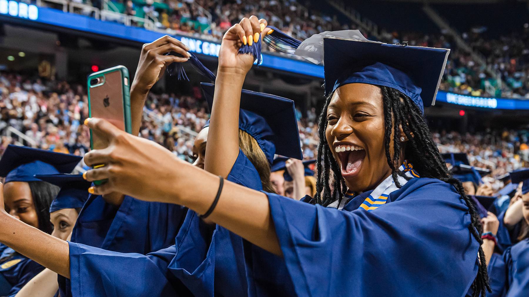 A student takes a selfie while turning her tassel at a commencement ceremony at the Greensboro Coliseum.