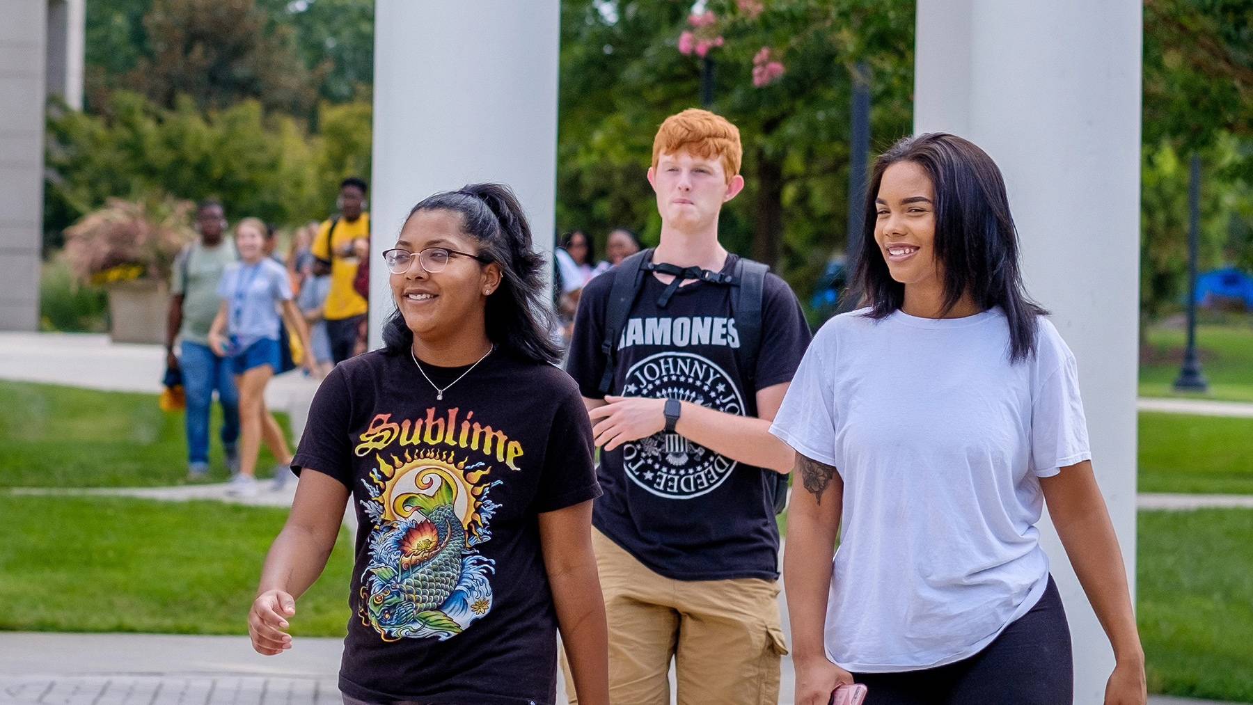 Students smile and talk while walking near the campus Clock Tower during SOAR.