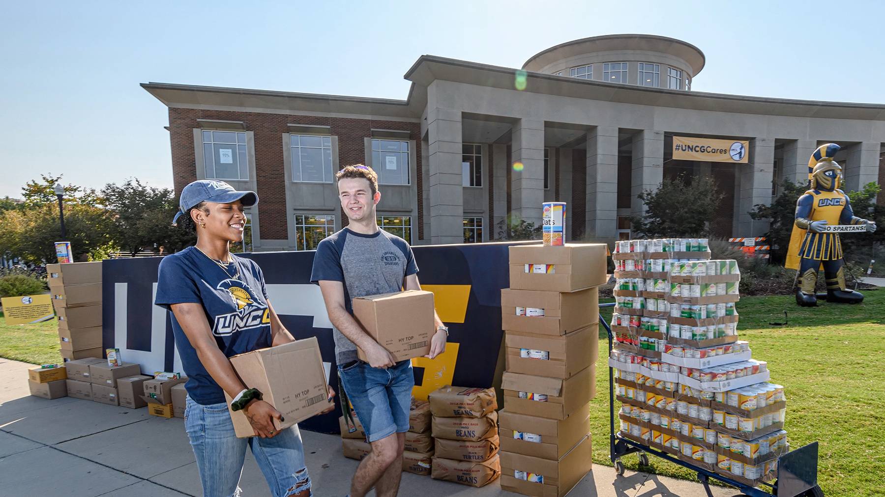 Two students carry boxes of canned goods outside of the Elliott University Center for donation to the Spartan Open Pantry.