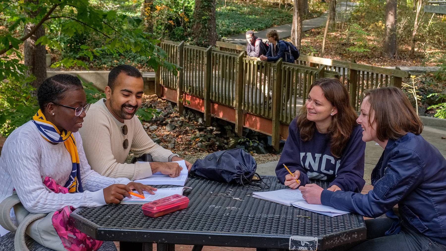 A group of students studies together at an outdoor table near Peabody Park.