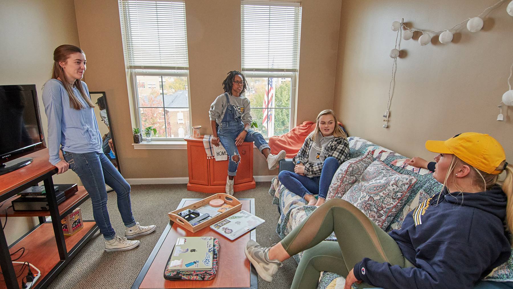 Four female UNCG students lounge in the living room of their Spring Garden Apartments suite.