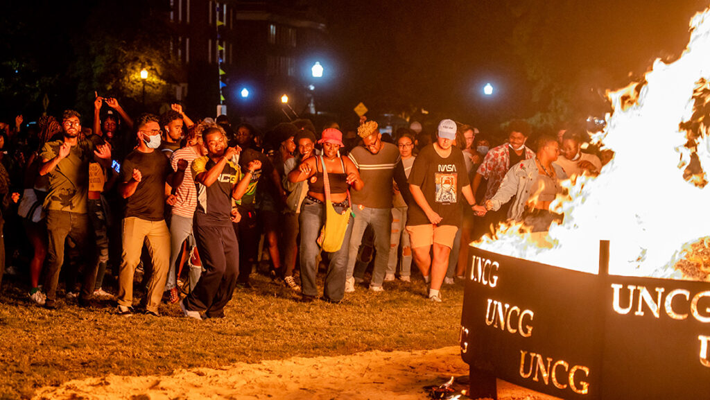 UNCG students dance beside the bonfire during the homecoming festivities.