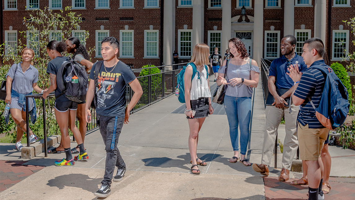 Two groups of students chat beside the bridge leading from the Petty Science Building.