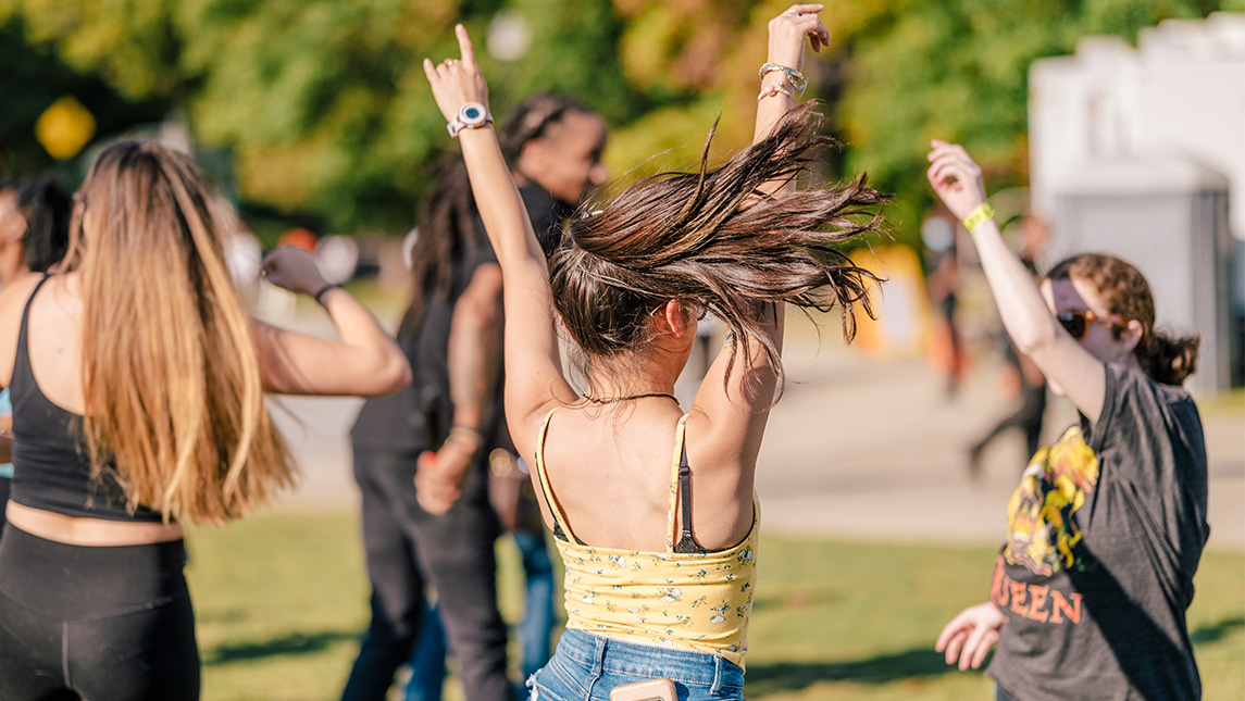 Dancer raises her hands at block party for 2022 Homecoming.