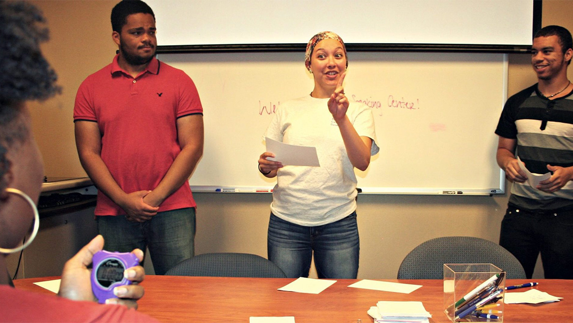 Students gather around a table with a stopwatch.