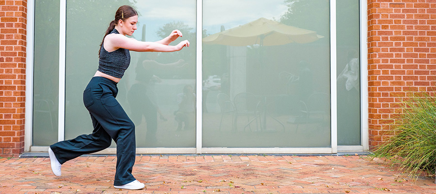 Woman dances in the Weatherspoon Art museum courtyard.
