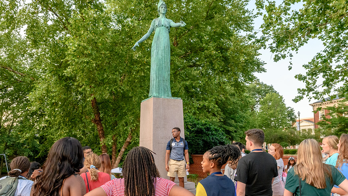 New students tour the UNCG campus around the Minerva statue.