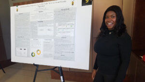 A woman stands next to her research poster at a conference.
