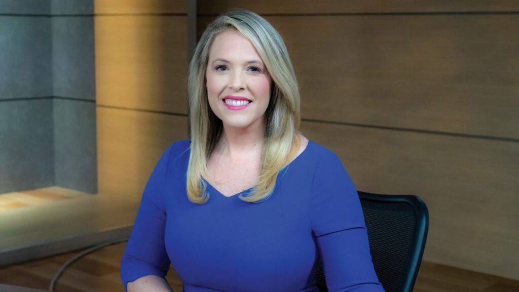Caroline Blair sits at news anchor desk