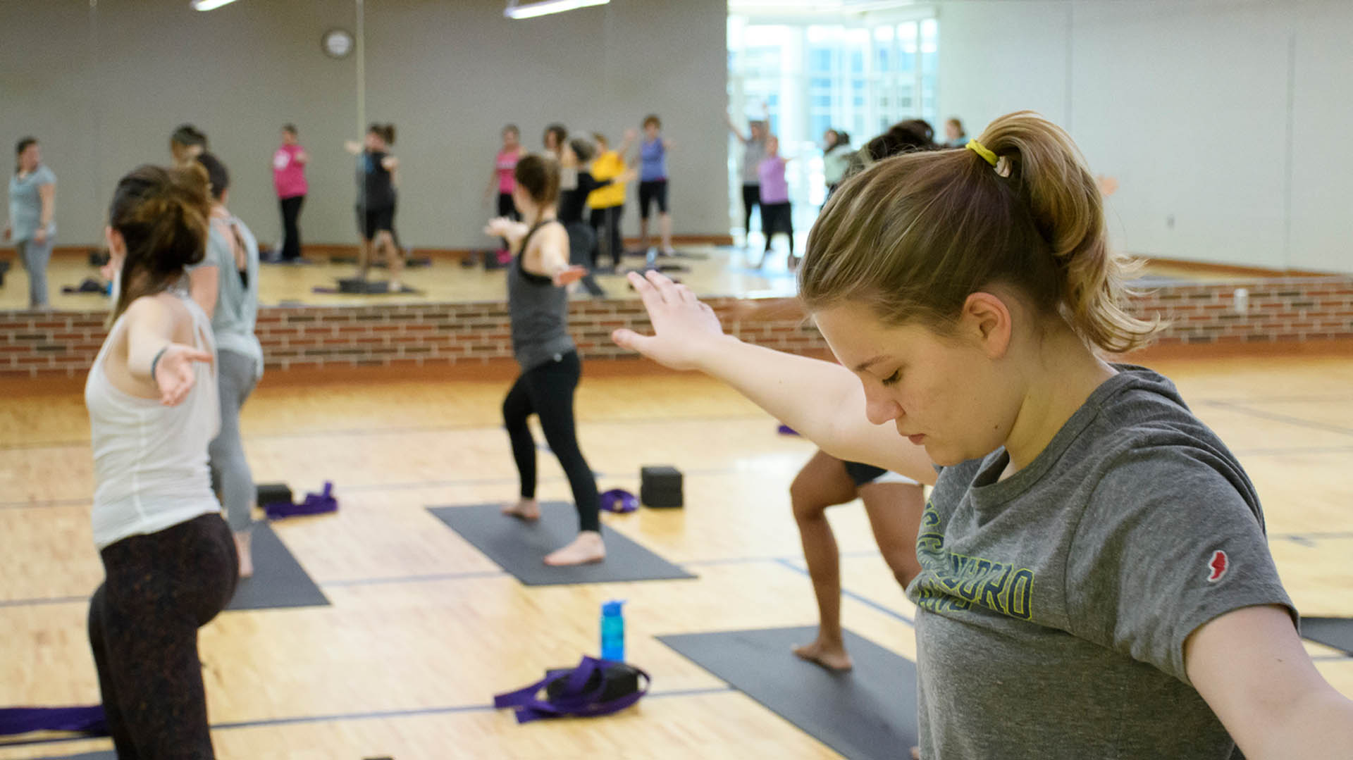 Young women hold a Warrior Two pose during a yoga class at the Kaplan Center.