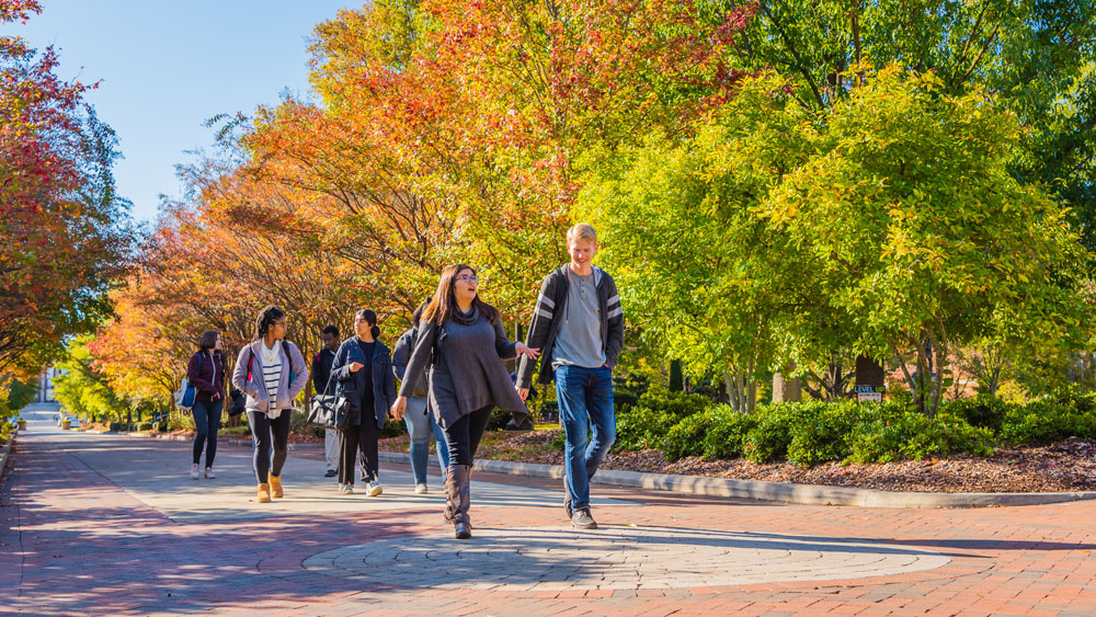 Students walking on College Avenue on UNCG’s campus in the fall.