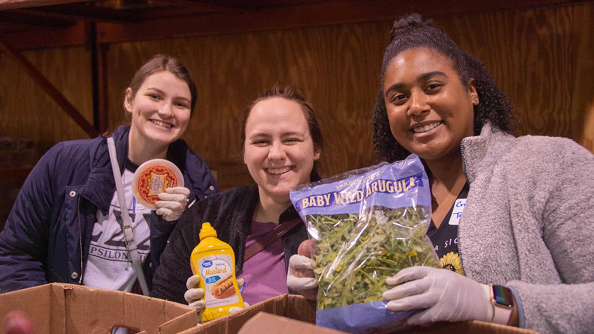 Three female UNCG students pose while sorting food at the Spartan Open Pantry during the annual MLK Day of Service
