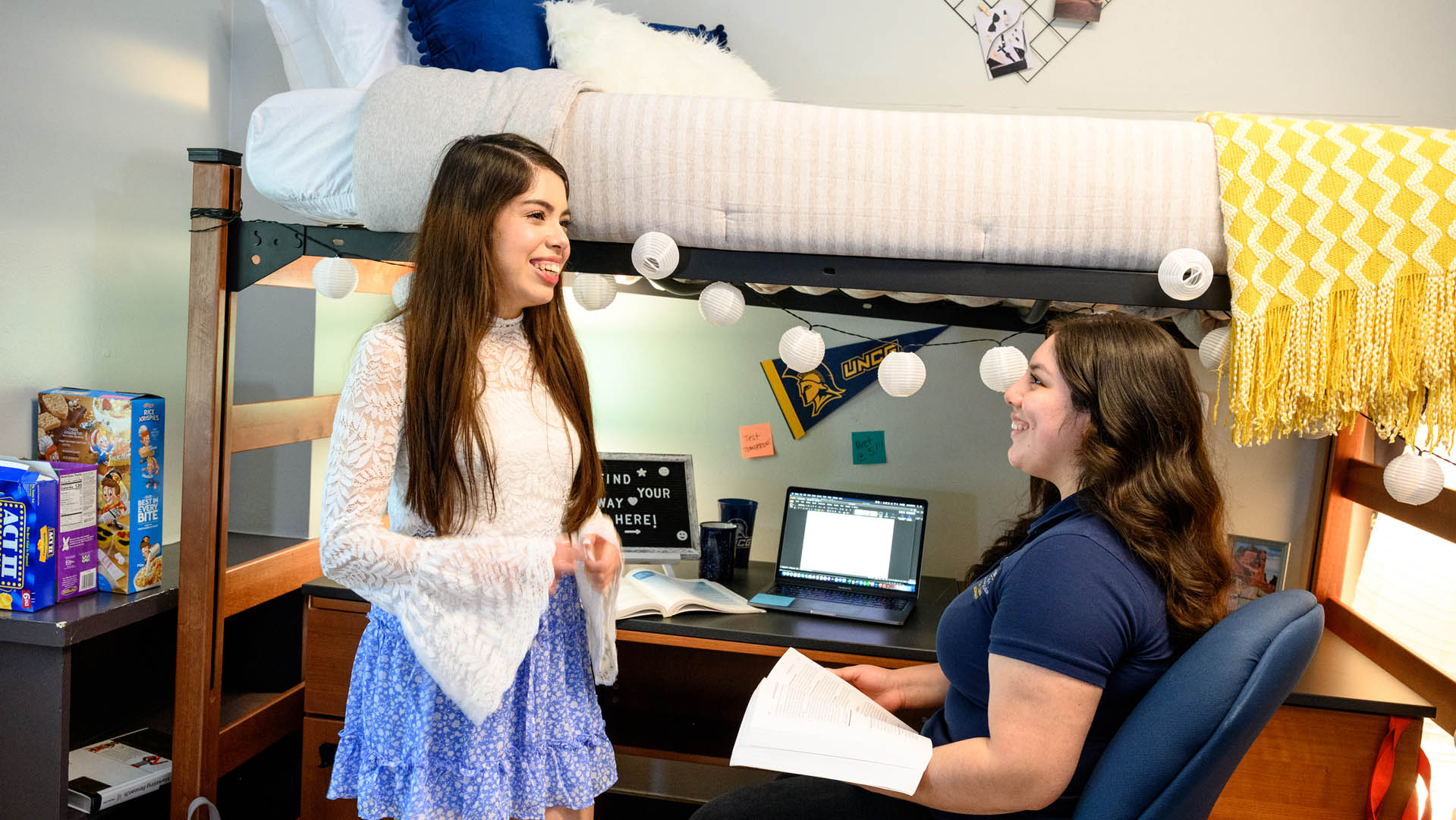 Two female students laugh while talking in their residence hall room.