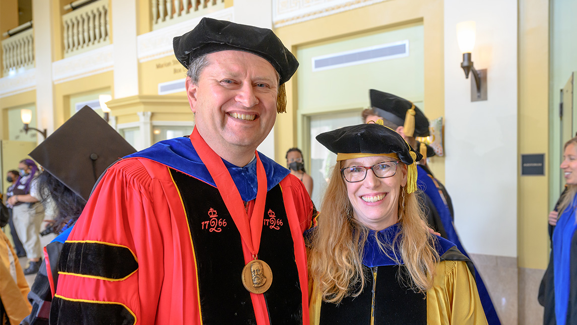 Faculty members smile in their commencement gowns and doctoral hoods.