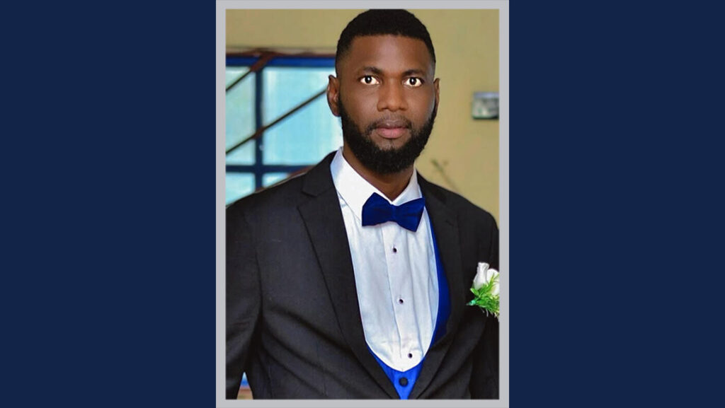 Shola Ishola poses in a suit and a blue bow tie.