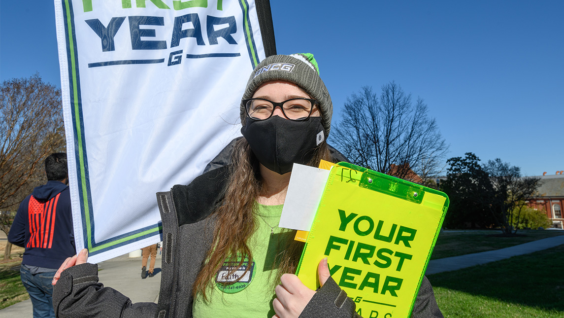 A student volunteer holds a clipboard reading 