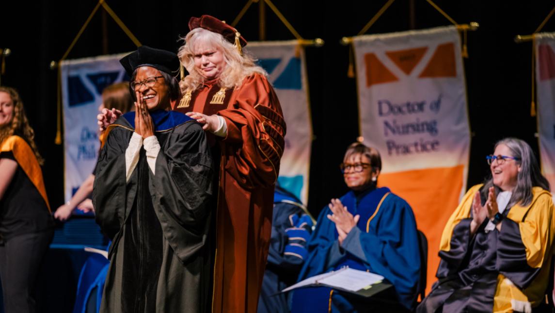 Emotional doctoral graduate receives hood 