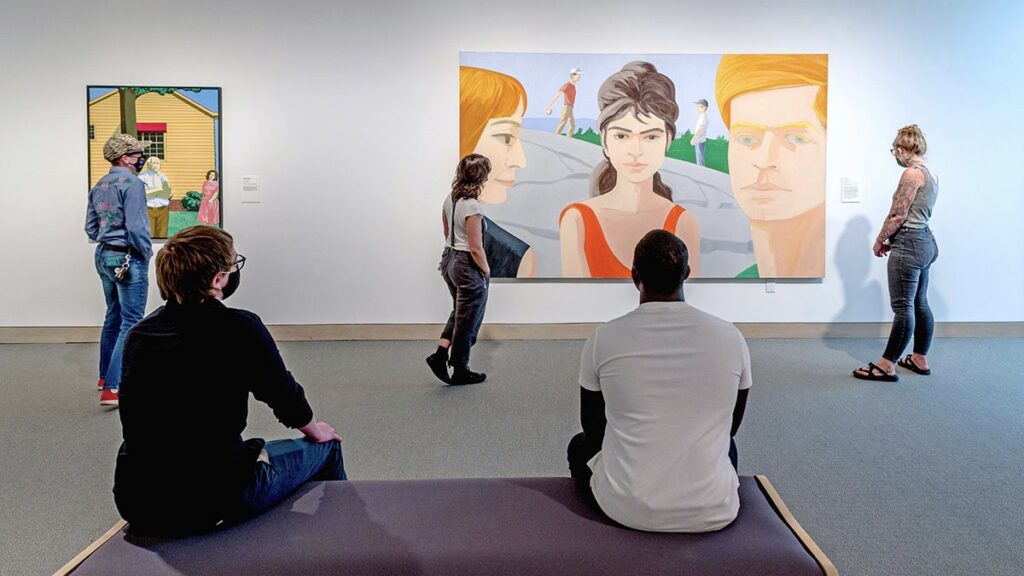 Students touring the Weatherspoon Art Museum look at paintings.