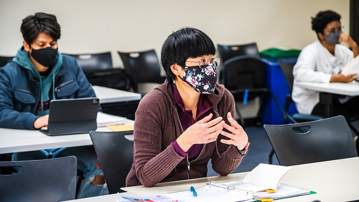 Students listen attentively in a classroom in masks.