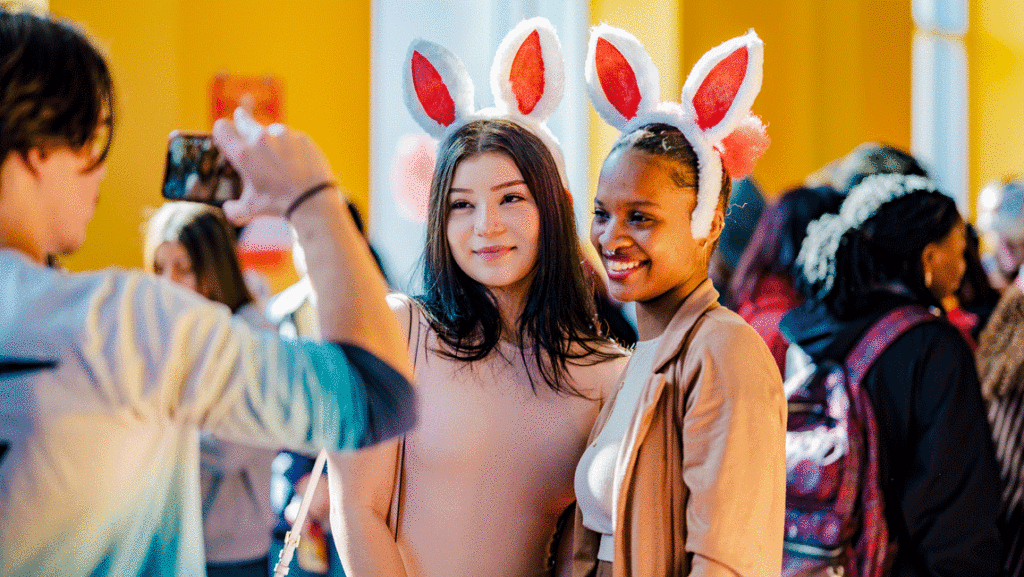 two students wearing rabbit ears take photos