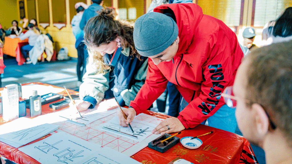 two students writing in Chinese calligraphy