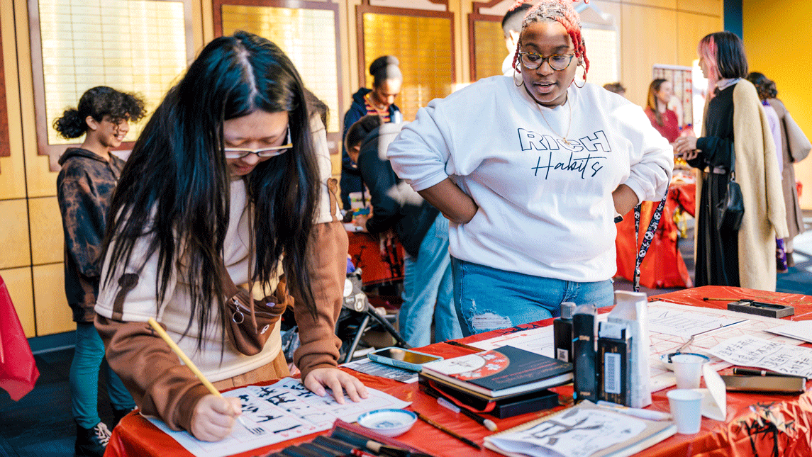 two women practicing Chinese calligraphy