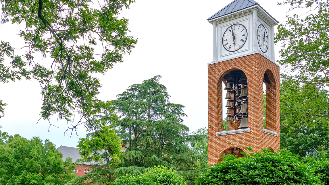 The UNCG clocktower surrounded by trees.