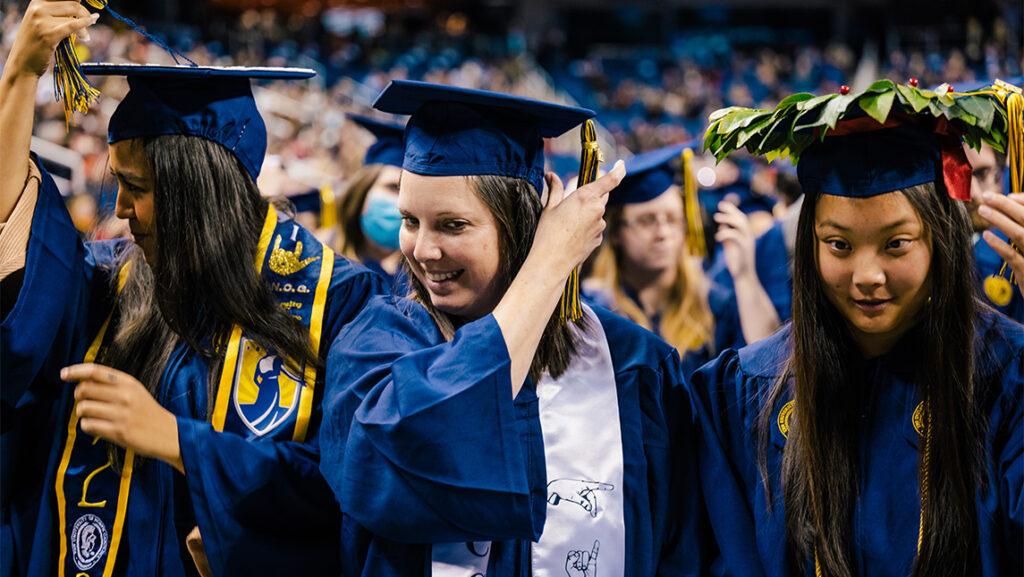 Three graduates turn their tassels at Commencement.
